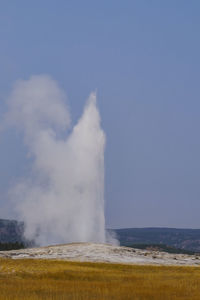 Steam emitting from volcanic landscape against clear sky