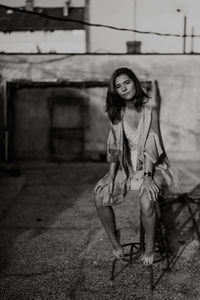 Portrait of young woman sitting on stool