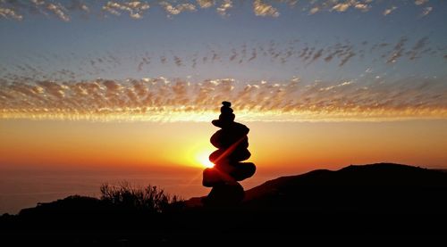 Silhouette of woman standing at sunset