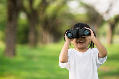 Portrait of boy holding sunglasses on field