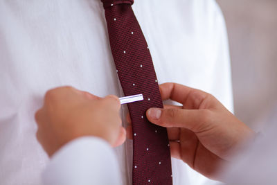 Cropped hands of man adjusting bridegroom necktie at wedding