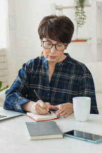 Young woman using mobile phone while sitting on table