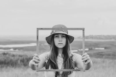 Girl straw hat holds empty wooden picture frame nature landscape portrait creative idea black white