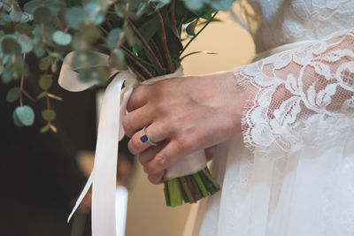 Midsection of bride holding bouquet