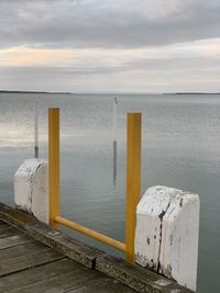 Wooden posts on pier over sea against sky