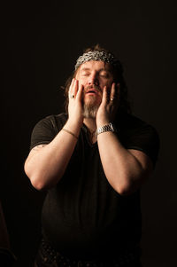 Portrait of man standing against black background