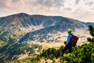 Woman looking away while standing on mountain against sky