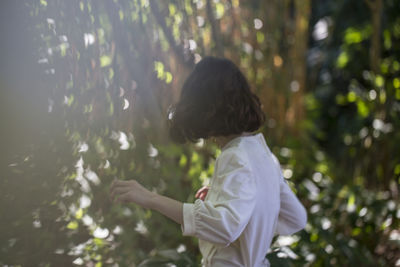 Rear view of woman standing in forest