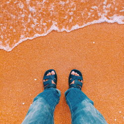 Low section of man standing on sand