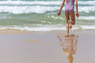 Low section of girl running on shore at beach