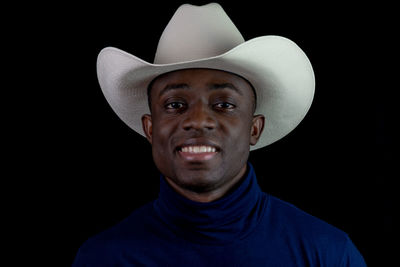 Portrait of man wearing hat against black background