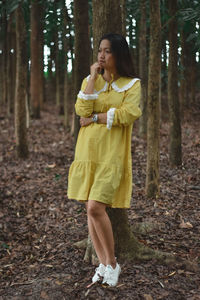 Full length of woman standing on tree trunk in forest
