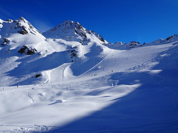 Scenic view of snowcapped mountains on sunny day