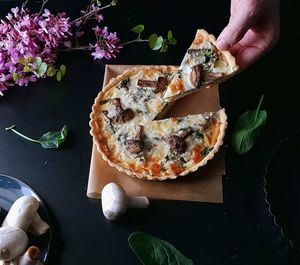 Cropped image of person hand holding pizza on table