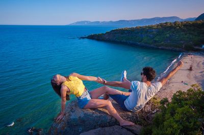 Couple holding hands against sea on cliff