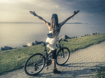 Rear view of young woman on bicycle at beach