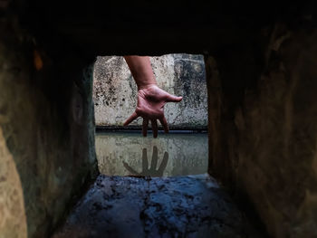 The reflection of a girl's hand fellon a water-filled cistern.