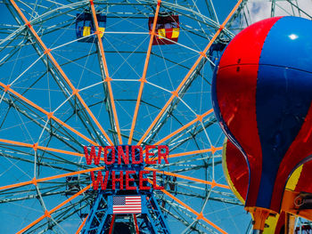 Low angle view of amusement park against blue sky