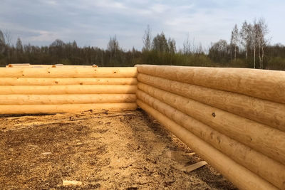 Stack of wood on field against sky