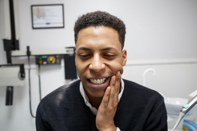 Close-up of young man with toothache sitting in hospital