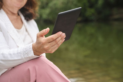 Midsection of woman using digital tablet