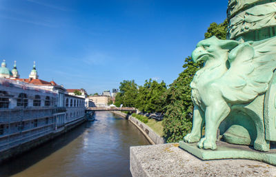 Statue of bridge over river against buildings