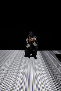 Full length of man sitting against black background