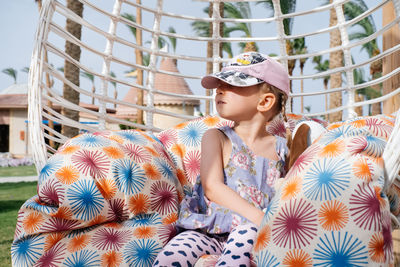 Serious toddler girl on the swing. stylish and moody child having rest. summer rest. conflicts. 