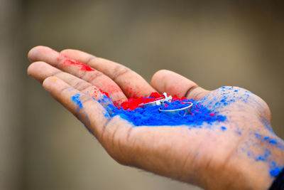 Cropped hand of woman holding powder paint with ring outdoors