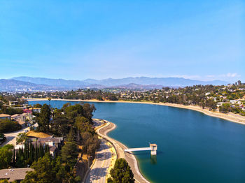 High angle view of river and cityscape against blue sky