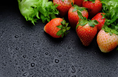 High angle view of strawberries with lettuce on wet table