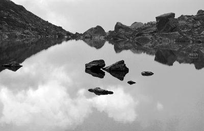 Reflection of rocks in lake against sky