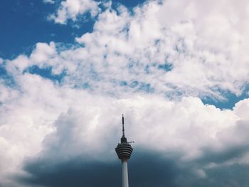 Low angle view of communications tower in city against sky