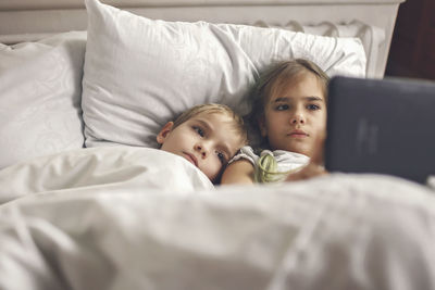 Siblings watching video in mobile devices in bed, gadget dependence and addiction, online lifestyle