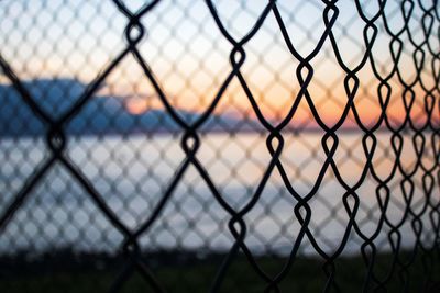 Chainlink fence against sky during sunset