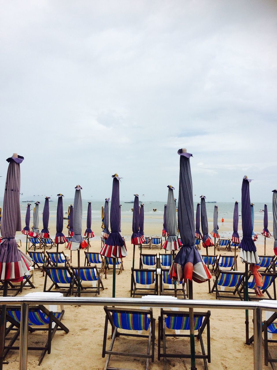 sky, chair, built structure, sea, architecture, beach, railing, building exterior, leisure activity, men, lifestyles, cloud - sky, day, person, table, outdoors, sitting, large group of objects, city