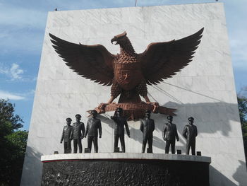 Low angle view of statues on building against sky