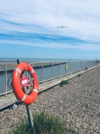 Red railing by sea against sky