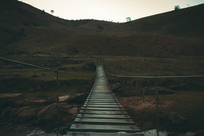 Boardwalk leading towards mountain against sky