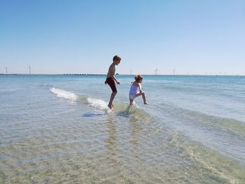 Children playing on beach against clear sky