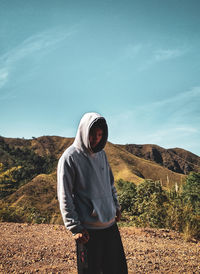 Man wearing hat standing on mountain against sky