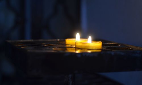 Close-up of illuminated tea light candles on table in building