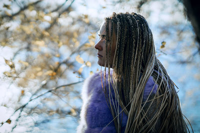 Side view of young woman against tree