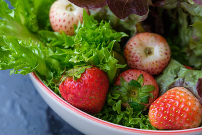 Close-up of strawberries with lettuce in bowl on table