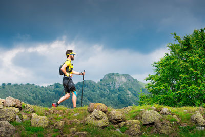 Male athlete alone practice nordic walking on mountain path