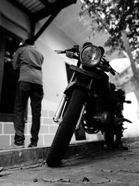 Close-up of motorcycle by man standing by wall