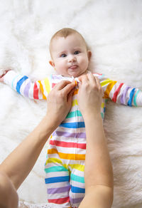 Mother taking care of baby girl lying on bed at home