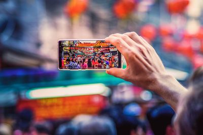 Close-up of man photographing crowd at street in city