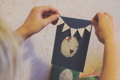 Cropped hands of woman holding greeting card at home