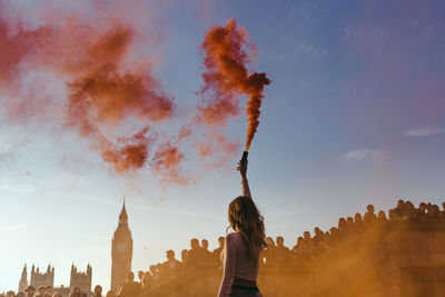 Rear view of woman with arms outstretched against sky